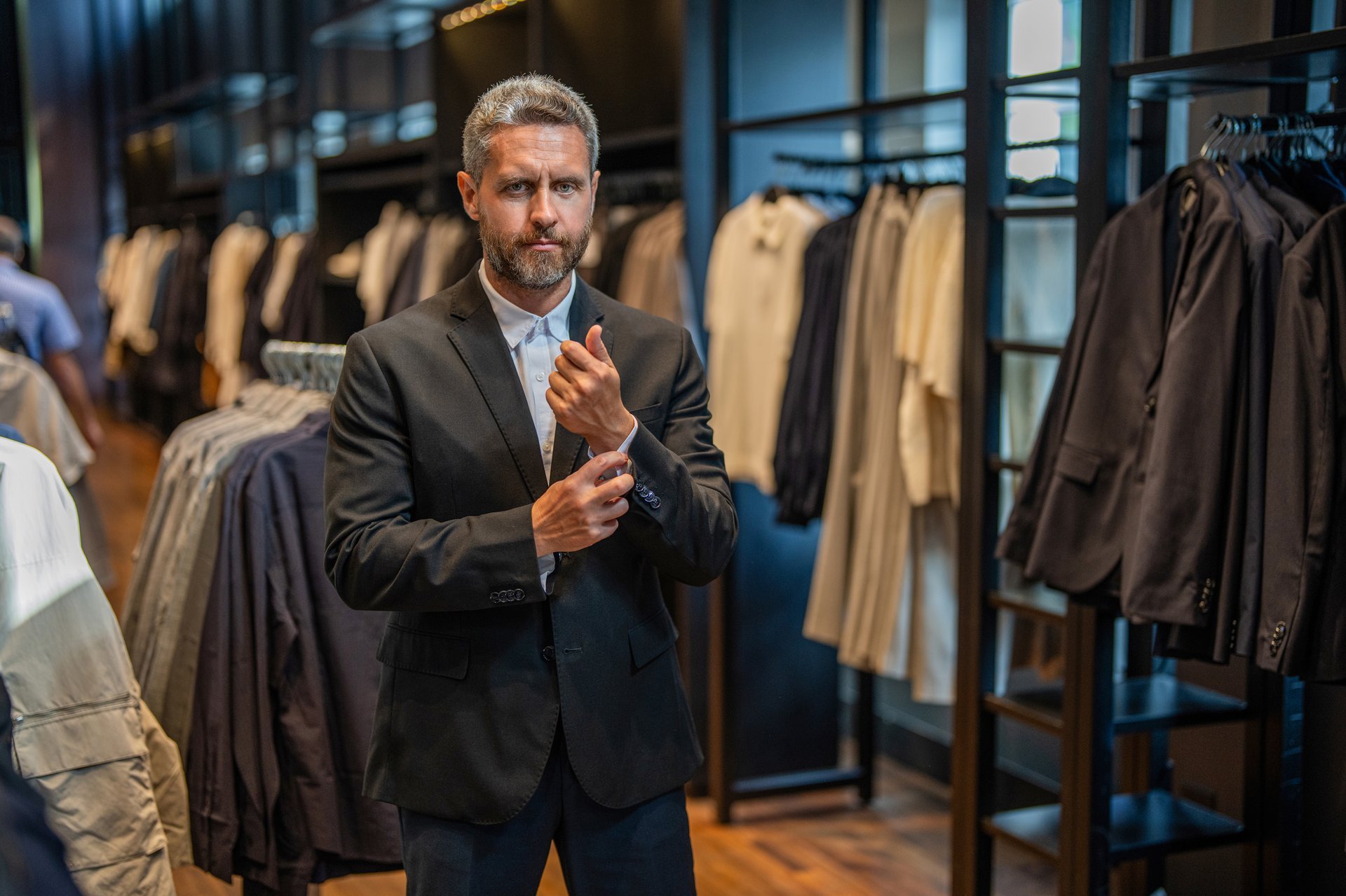 Stylish man choosing suit in boutique