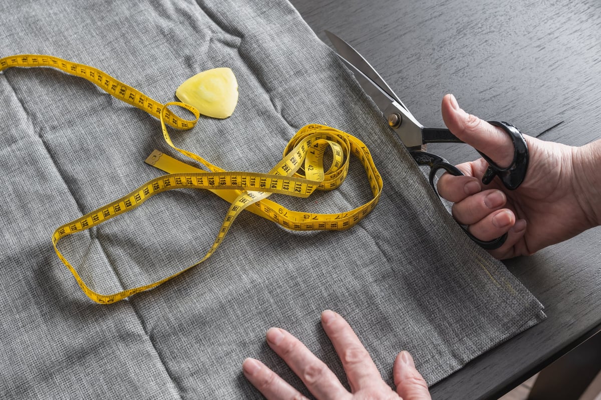 Hand cutting fabric with scissors and measuring tape